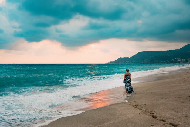 Woman in long dress walking on seashore