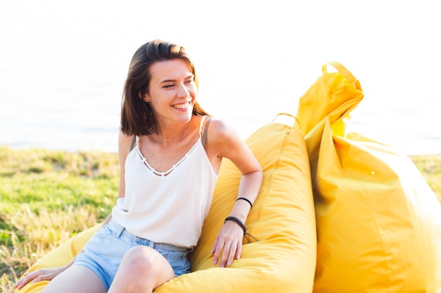 Free Photo woman looking away while sitting on yellow beanbag