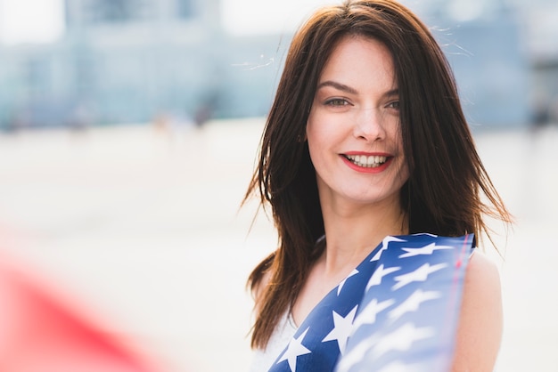 Woman looking at camera and smiling waving with stars of American flag