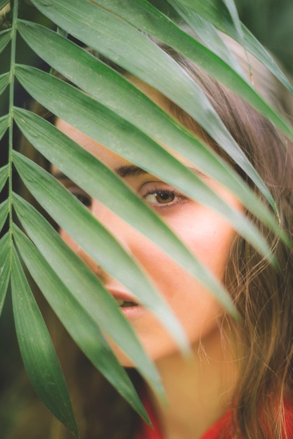 Free Photo woman looking at camera through leaves