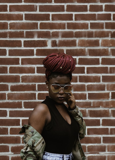 Woman looking downwards in front of brick wall