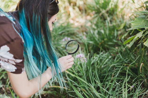 Free photo woman looking at flowers through magnifying glass