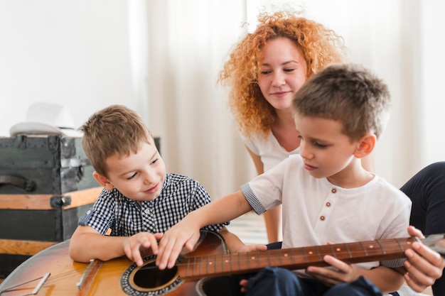 Free photo woman looking at her children playing guitar