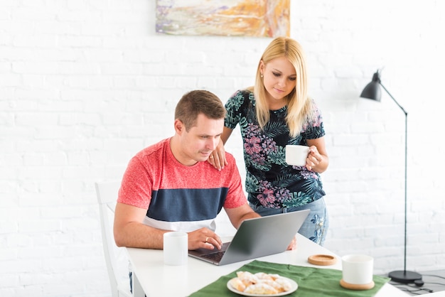 Free photo woman looking at her husband working on laptop