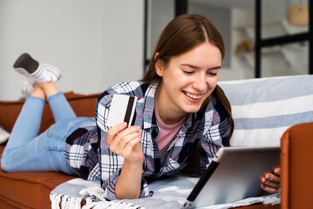 Free photo woman looking at her tablet and holding a credit card