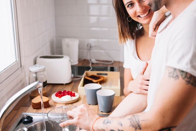 Free Photo woman looking at man washing dishes