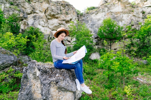 Woman looking at map sitting on a rock