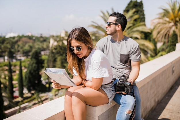 Woman looking in map sitting with her boyfriend in the park