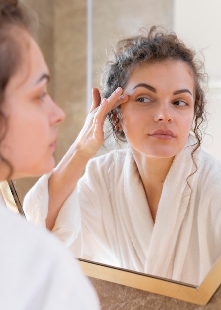 Woman looking in mirror and doing beauty face routine