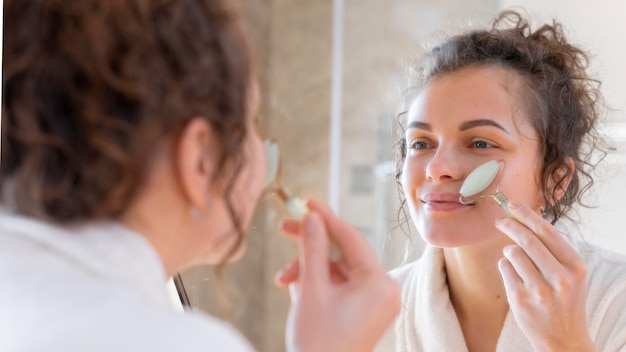 Woman looking in mirror and doing face massage