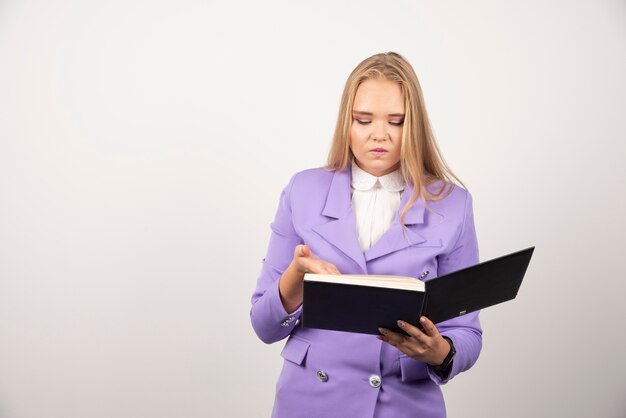 Woman looking on opened tablet on white wall. 