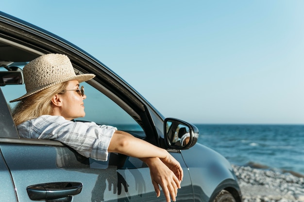 Woman looking out of car window looking at sea