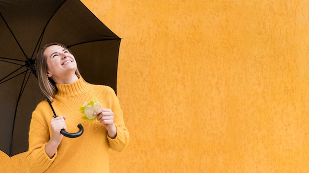 Free Photo woman looking up while holding an umbrella with copy space