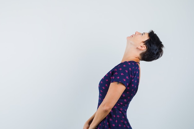 Free photo woman looking upward while bending head back in dress and looking focused .