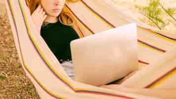 Free photo woman lying in hammock with laptop