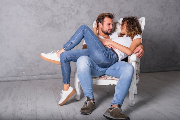 Woman lying on man in armchair 