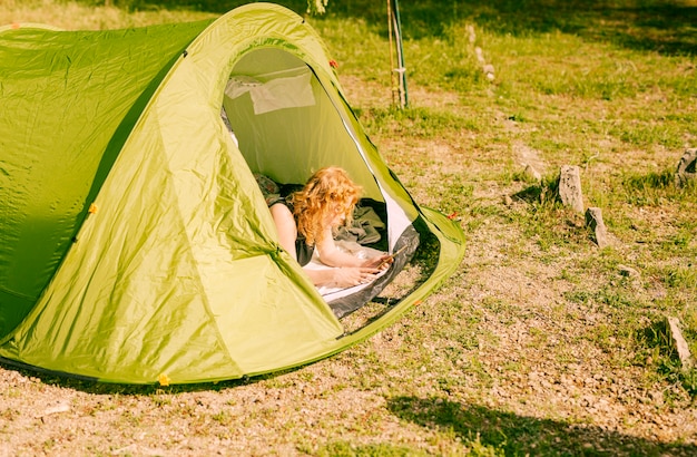 Free photo woman lying in tent with tablet