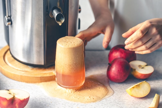 Free photo a woman makes apple juice at home with a juicer