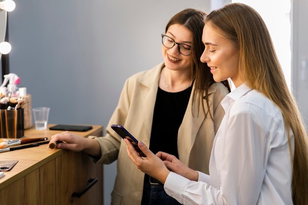 Woman and makeup artist looking at phone