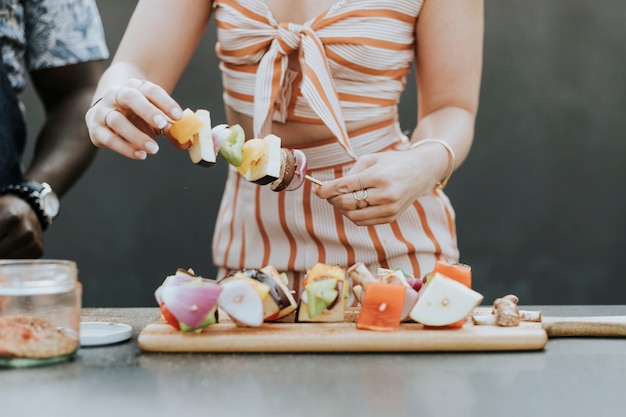 Free Photo woman making barbeque skewers for a party