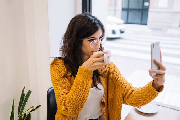 Woman making photo of herself in cafe