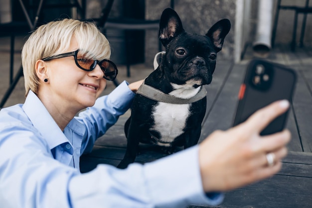 Free photo woman making selfie photo with her pet french bulldog