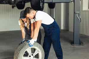 Free photo woman and man at auto service changing wheels