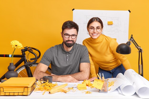 Woman and man developers create architect project use blueprints sketches look happily, after successful working day have productive cooperation 