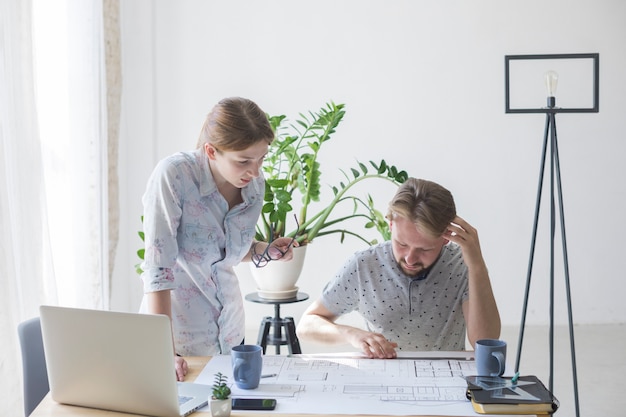 Free Photo woman and man looking at blueprint while working in office