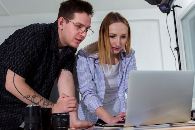 Free photo woman and man looking through photos on laptop