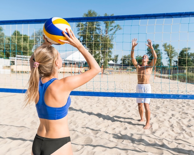 Free Photo woman and man playing beach volleyball together