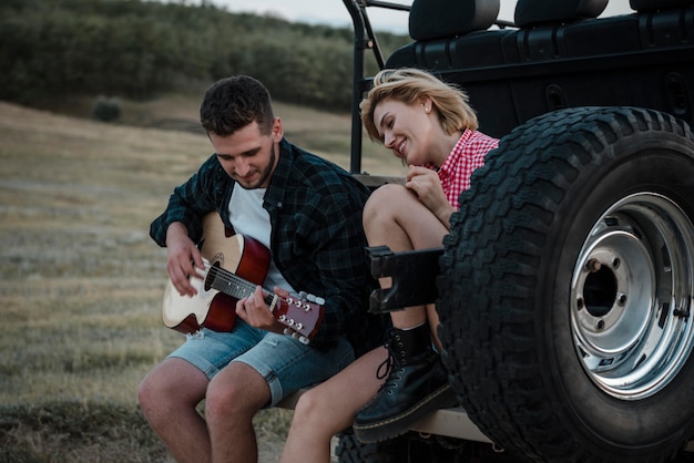 Free photo woman and man playing guitar while traveling by car