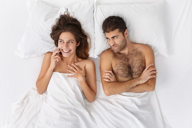 Woman and man sitting in bed top view