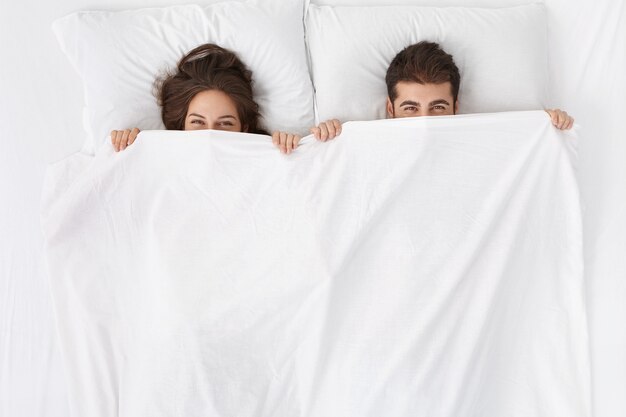 Woman and man sitting in bed top view