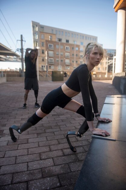 Woman and man with leg disability exercising in the city