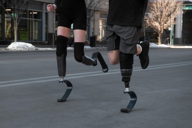 Free photo woman and man with leg disability running in the city