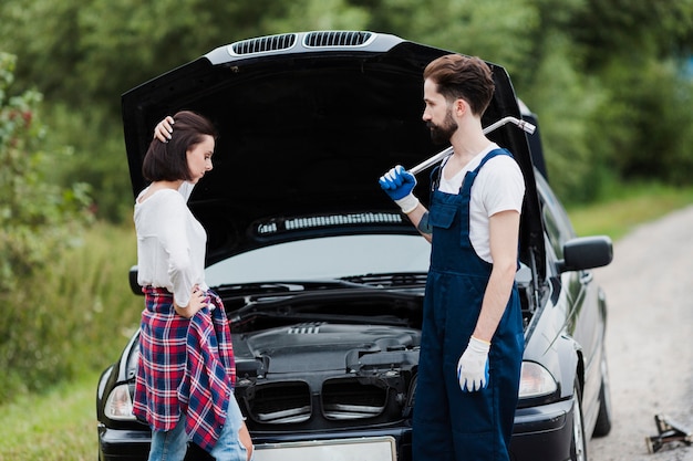 Woman and man with open car hood