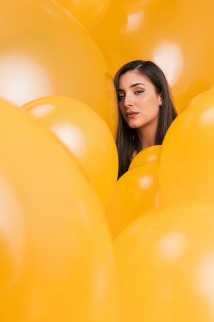 Woman between many yellow balloons