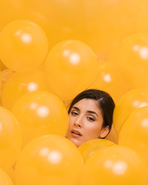 Woman between many yellow balloons