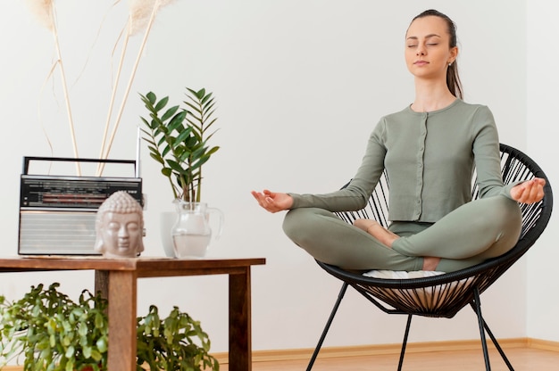 Free photo woman meditating at home on chair