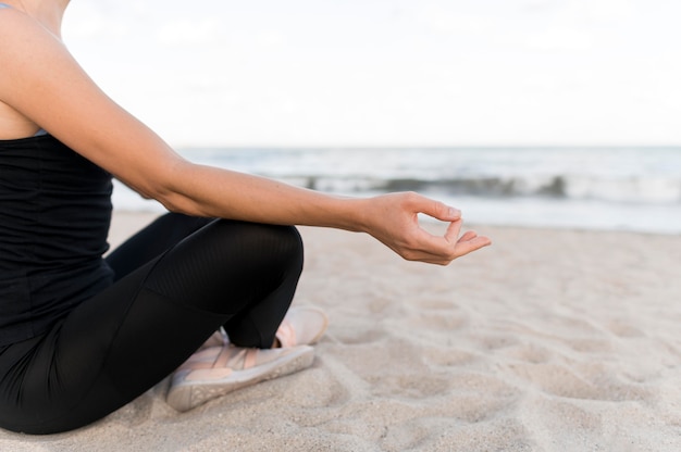 Woman meditating in the lotus position on the sand