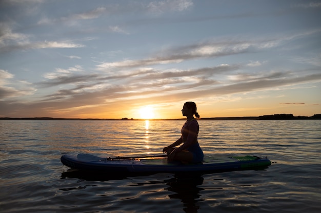 Woman meditating on paddleboard side view