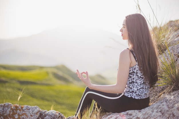 Free Photo woman meditating on rock