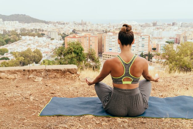 Woman meditating with the city at the background