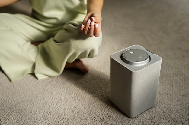 Free photo woman meditating with smart speaker high angle