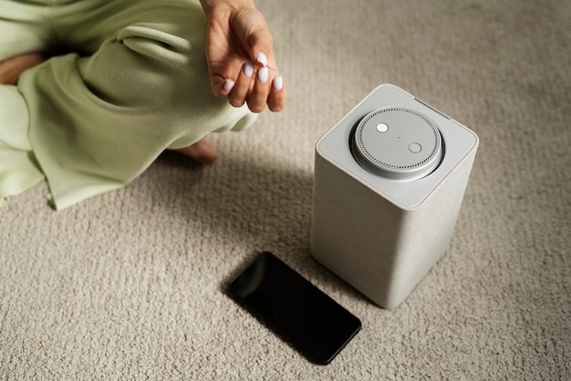 Free photo woman meditating with smart speaker high angle