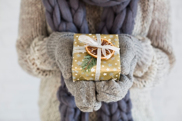 Woman in mitts and scarf with present box in hands