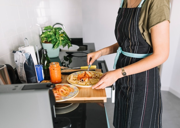 Free photo woman mixing the sauce in the pasta on kitchen counter