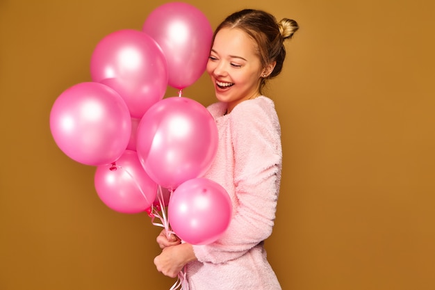 Woman model with pink air balloons on golden wall