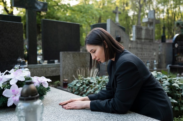 Free Photo woman mourning in the cemetery next to grave